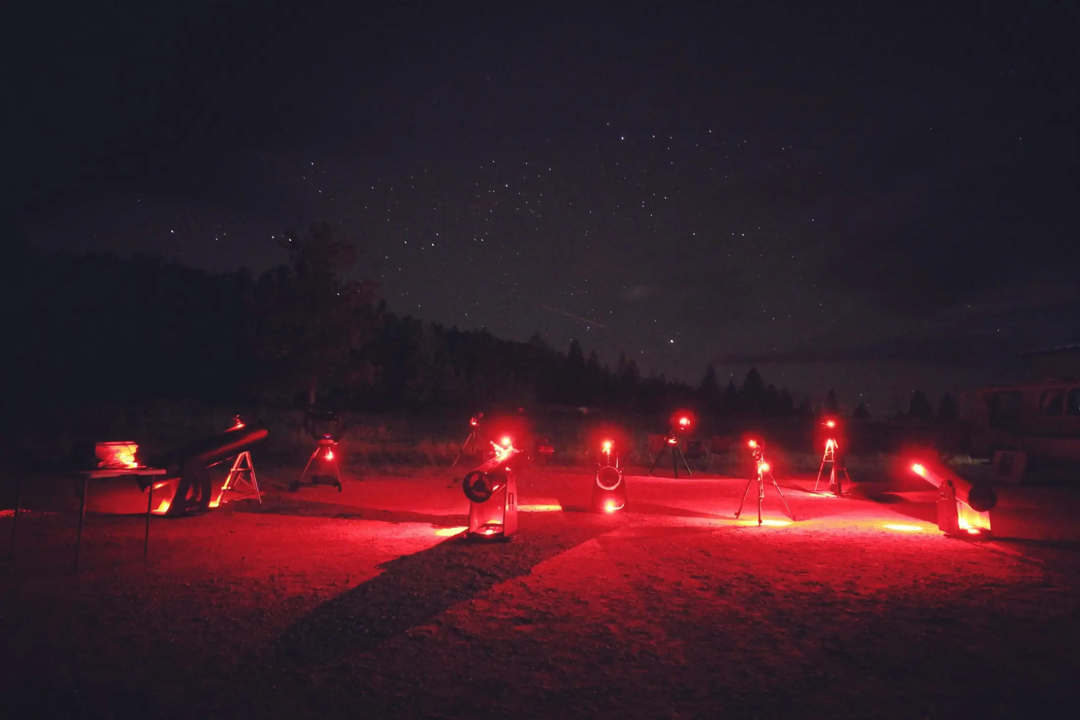 A line of telescopes glowing red beneath a dark sky