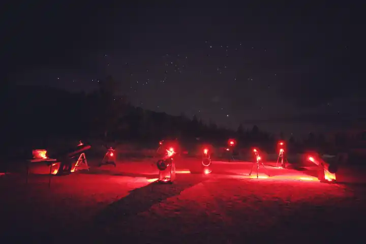 Telescopes arranged under red observing lights in Colorado's San Luis Valley region, photographed by AstroTours.org.