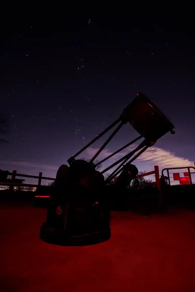 A large telescope silhouetted beneath a star-filled sky during an AstroTours.org observing night.